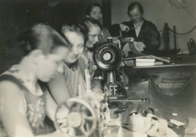 Arbeiterinnen und Familienmitglieder in der Mützenmacher-Werkstatt von Paul Brand
